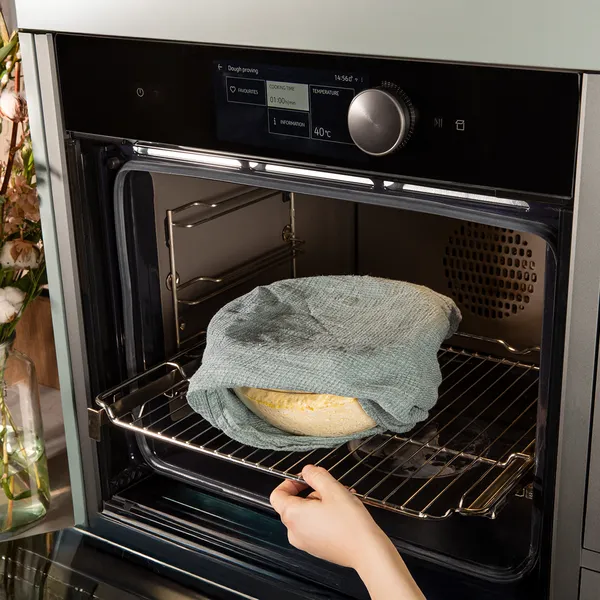 Oven with baking dish containing a pie or pastry, hand reaching to remove it.