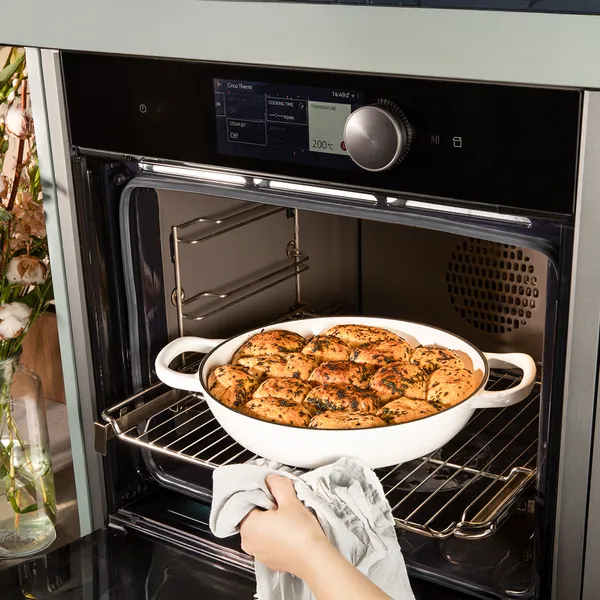 Baked casserole dish in oven, surrounded by kitchen appliances and greenery.