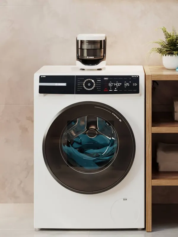 A bright laundry room with plants and a Bosch Microplastic Filter standing on top of a washing machine.