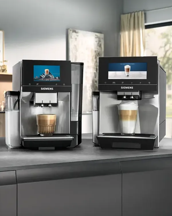 Två Siemens kaffemaskiner på en köksbänk, var och en med ett latteglas under pipen och digitala displayer som visar kaffebilder.