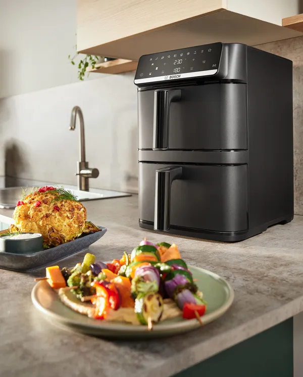 Air Fryer z podwójnym koszem w kuchni na blacie z talerzmi z jedzeniem