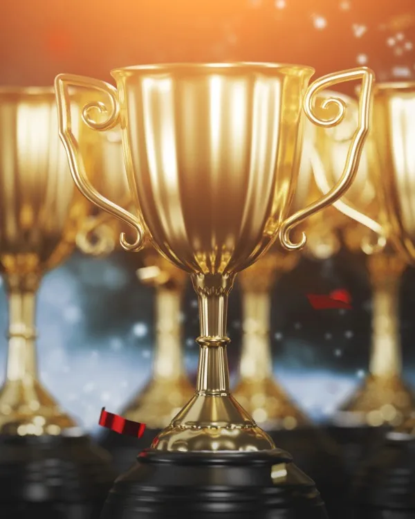 Three golden winners cups with a dark background and confetti