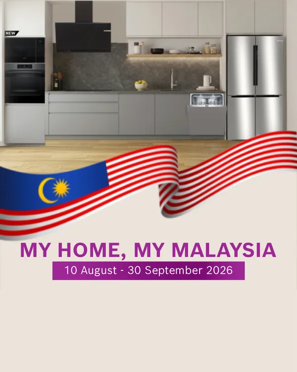 Promotional National Day banner featuring a contemporary kitchen with grey cabinetry, built-in oven, range hood, dishwasher, and stainless steel refrigerator. A large Malaysian flag ribbon waves across the top of the image. Text reads "MY HOME, MY MALAYSIA" and "10 August - 30 September 2026."