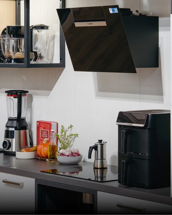 Főzőlap felett egy szagelszívó, mellette Air Fryer és turmixgép.