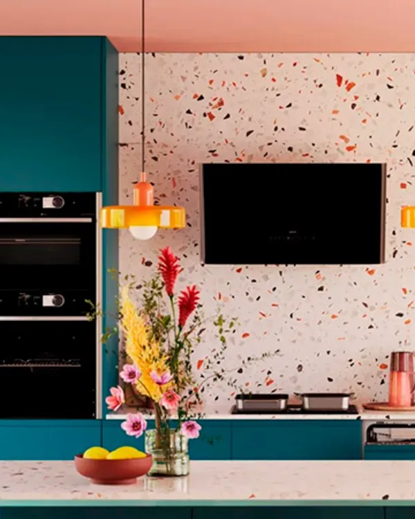 Farbenfrohe, moderne Küche mit Terrazzo-Arbeitsplatte, Einbaugeräten und einem lebhaften Blumenarrangement.