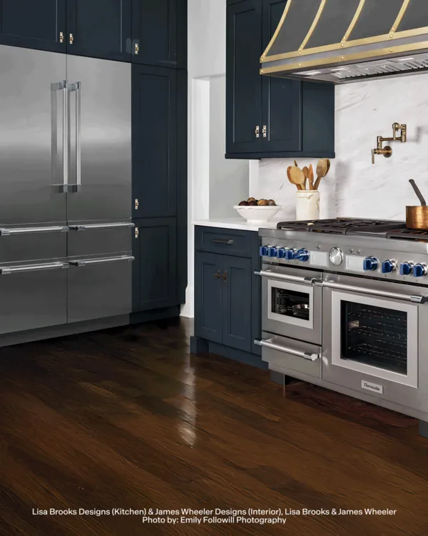 Modern kitchen with Thermador stainless steel appliances, dark brown wooden floor, and navy colored cabinets
