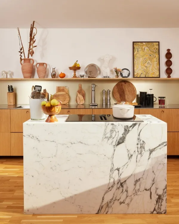 Cucina accogliente con piano in marmo, mobili in legno e oggetti decorativi sulle mensole.