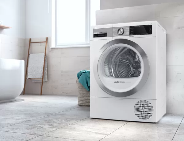 Bosch washer in a bathing room with a laundry basket next to the washer and a bath tub in the background.