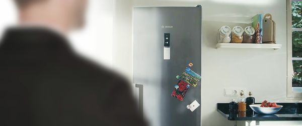 A man going into a kitchen to a fridge with Home Connect function