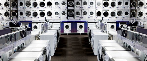 Large room and a wall full of Wi-Fi-enabled washing machines and dryers with Home Connect