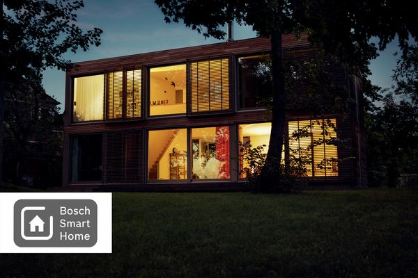 Zářivě osvětlený moderní dům s bezpečnostním systémem Bosch Smart Home.