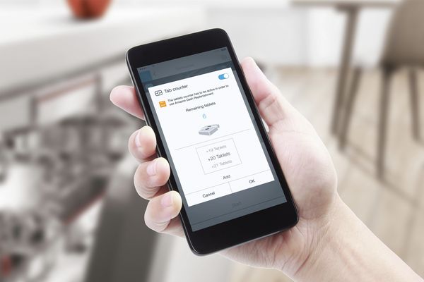 Connexion d'un compte Home Connect à un compte Amazon sur un smartphone dans une cuisine connectée avec un lave-vaisselle Home Connect.