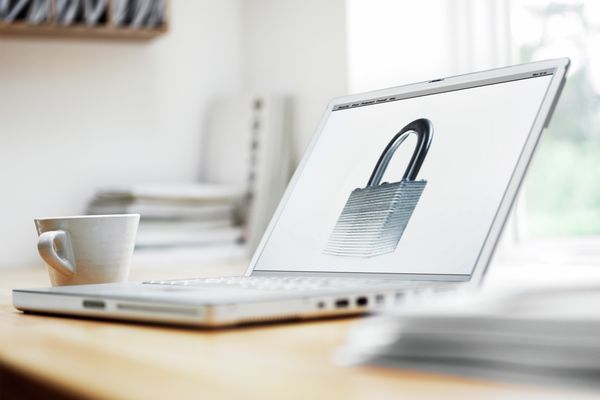 Computador portátil numa mesa com um símbolo de privacidade no ecrã, simbolizando a proteção de dados da Home Connect