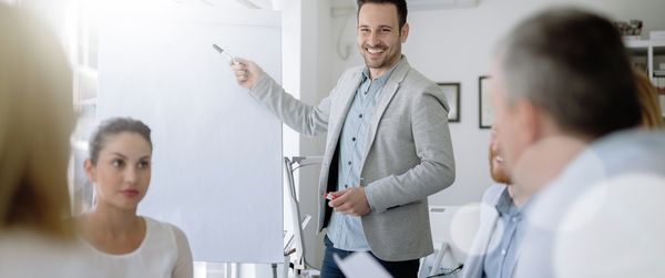Un jeune homme avec un tableau de conférence, présentant les avantages de Home Connect à des partenaires potentiels
