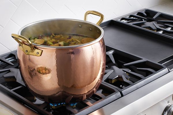 Cuisinière et soupe dans une casserole en cuivre 