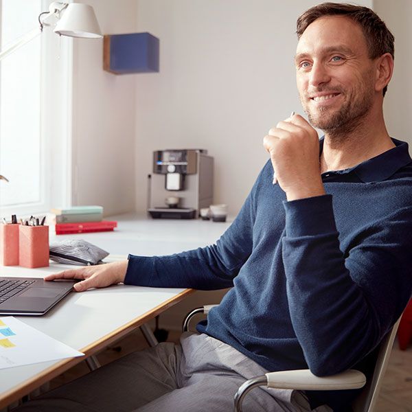 Muž používajúci aplikáciu Home Connect na riadenie chodu svojich pripojených domácich spotrebičov z kancelárie.