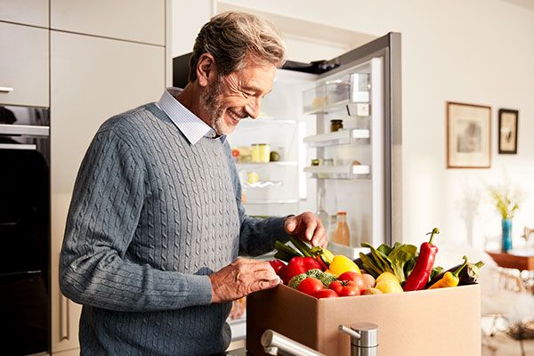 Man unpacks fruit and vegetable package, ordered through Home Connect partner Avocando