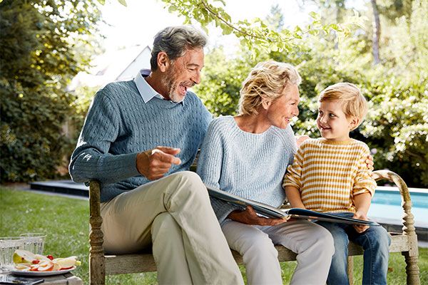 Grandparents are sitting in the garden with their grandson showing him the Home Connect app