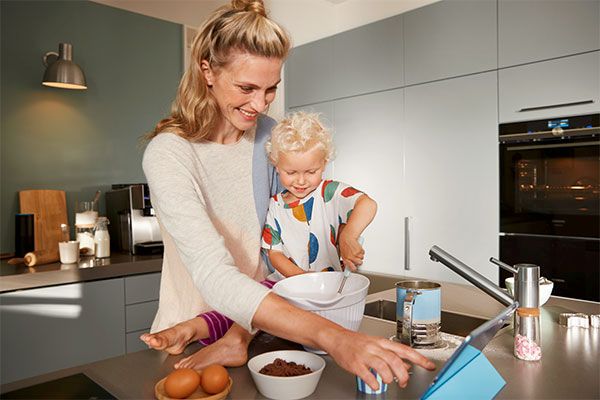 Uma criança a fazer um bolo com a mãe e a ligar o forno Home Connect para o pré-aquecimento com um comando de voz da Alexa.