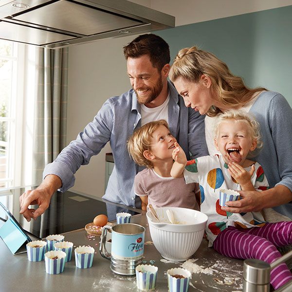 Uma família no sofá a usar a aplicação Home Connect com entusiasmo.
