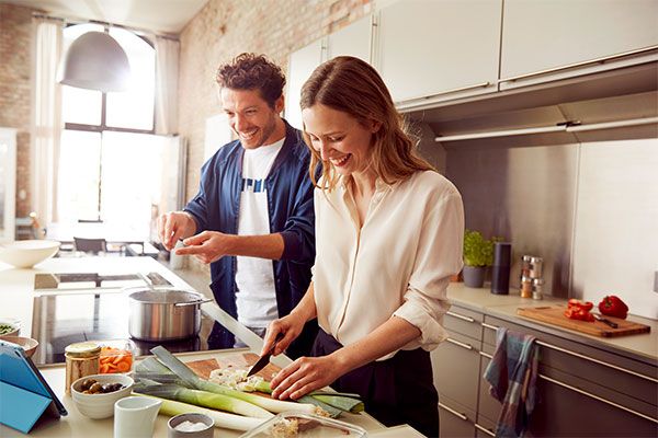 Couple cooking together; also the stove with Home Connect has a pot of boiling water