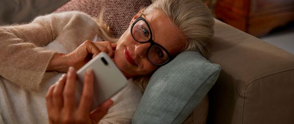 Woman lies on the sofa with her smartphone.