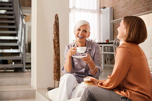 Two women are having coffee and laughing together.