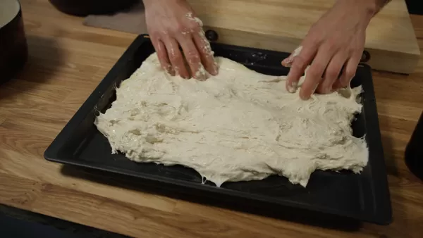 Focacciadeig formes med hendene på en benkeplate 
