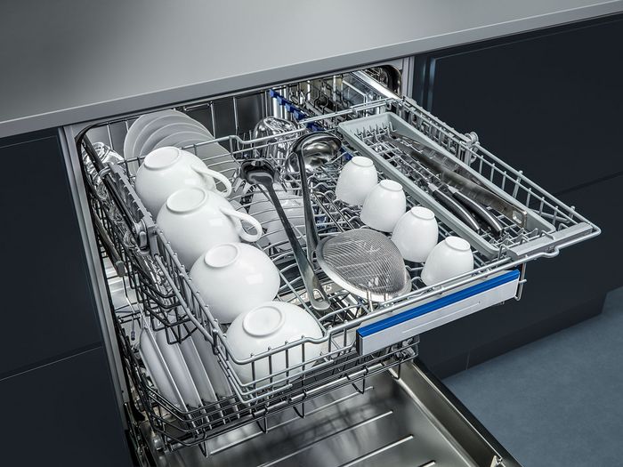 Lavastoviglie Siemens aperta con cestelli estraibili carichi di tazze e stoviglie 