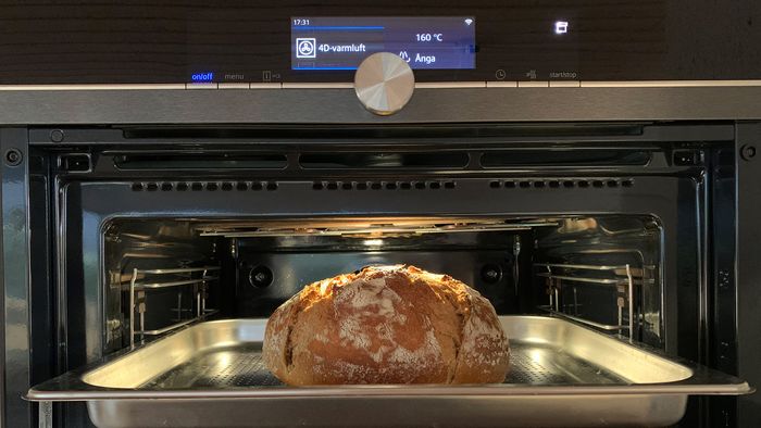 Otwarty piekarnik parowy w którym znajdują się bochenek chleba