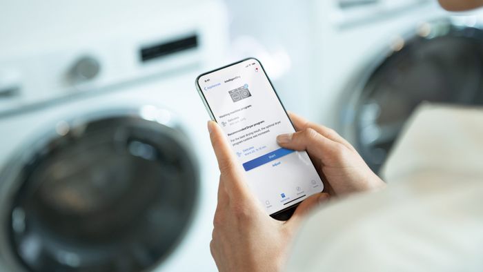 Un usuario empareja su lavadora y secadora inteligentes iQ700 de Siemens en la pantalla de su m&oacute;vil con la app Home Connect