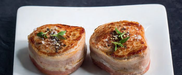 Deux filets de porc enrobés de bacon présentés dans un plat. 