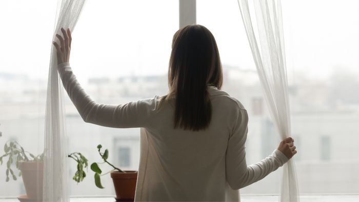 Donna che apre una finestra in casa