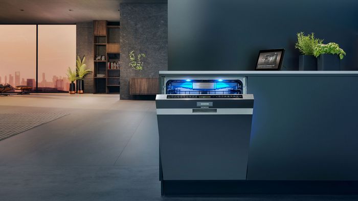 מדיח כלים מובנה חלקית במצב פתוח עם תאורה כחולה, במטבח מודרני כהה.          