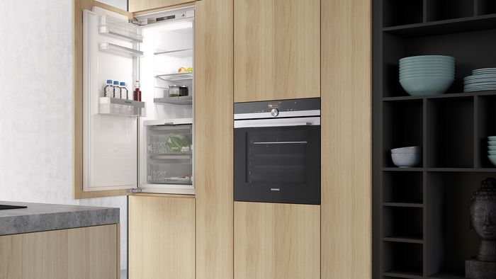 Multiple intergrated appliances in kitchen along with fridge with door open showing interior
