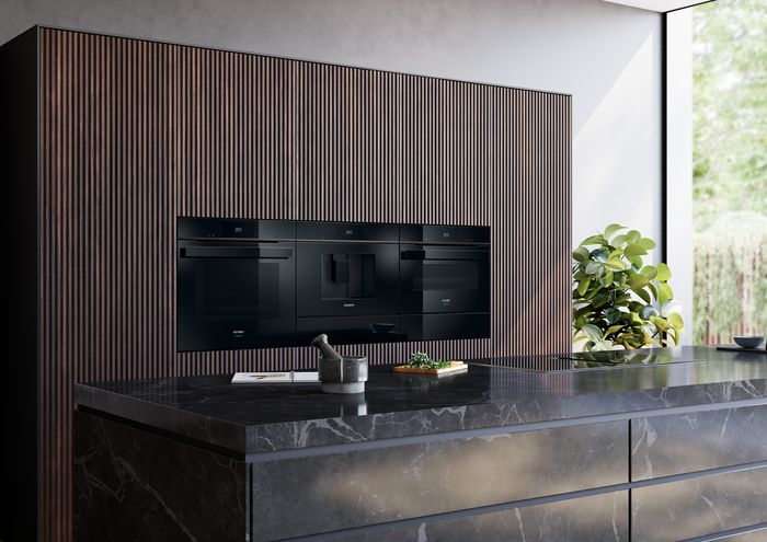 Elettrodomestici da incasso Siemens installati in una parete attrezzata con finitura in legno, in una cucina con isola