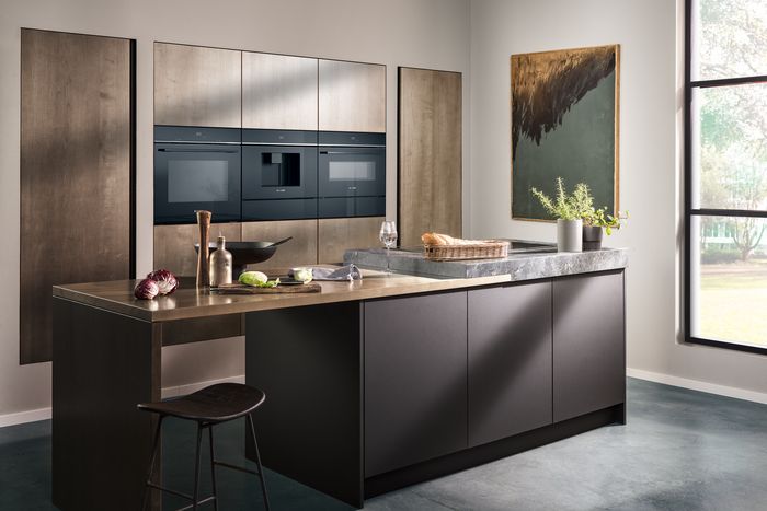 Moderní kuchyně s dřevěnými skříněmi, černými pulty a vestavěnými spotřebiči. 