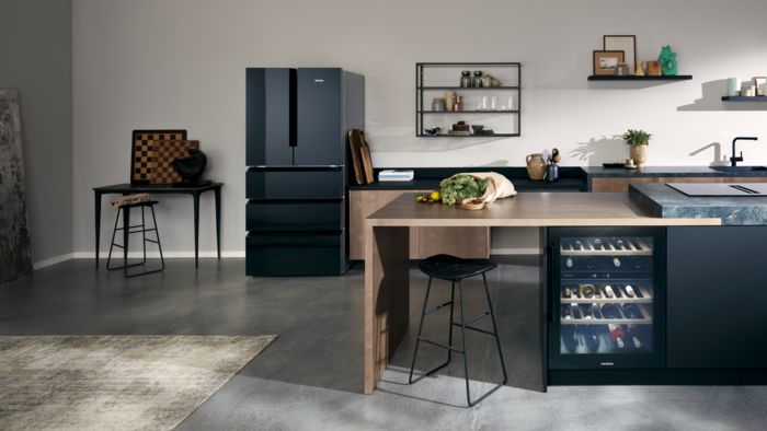 Eine edle Küche, ausgestattet mit hochwertigen Geräten wie einer Kühl-Gefrier-Kombination und einem Weinkühlschrank, befindet sich in modernem Ambiente.