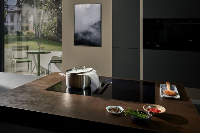 Piano cottura a induzione Siemens con cappa integrata, installato sull&rsquo;isola della cucina, con pentola in ebollizione