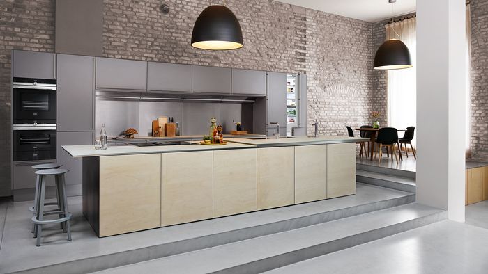Open space con cucina moderna, illuminazione a sospensione ed elettrodomestici da incasso 