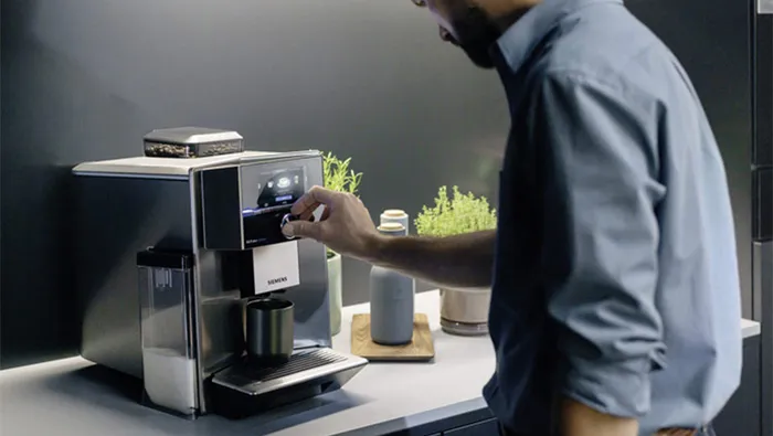 Osoba przygotowuje aromatyczną kawę w ekspresie stojącym na blacie w kuchni