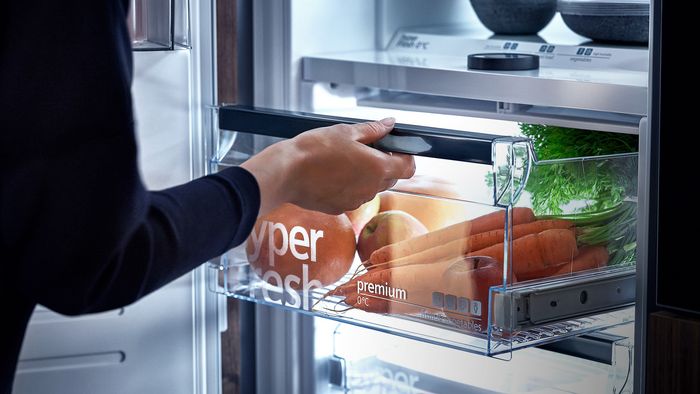 In einer Kühl-Gefrier-Kombination von Siemens wird die hyperFresh-Schublade mit frischem Gemüse herausgezogen