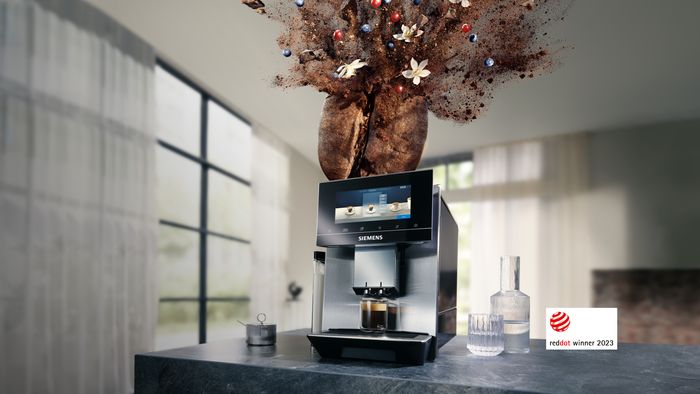 A Siemens coffee machine brewing espresso, with an artistic explosion of coffee beans, grounds, berries, and flowers above it, and a "Red Dot Winner 2023" badge.