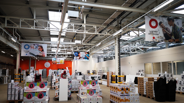 Grand magasin intérieur avec étagères, présentoirs et signalisation pour divers produits.