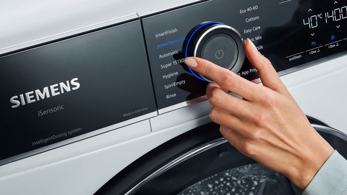 Eine Hand stellt das Waschprogramm an einer Siemens Frontlader-Waschmaschine ein.