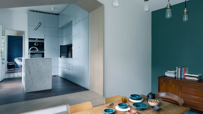 Cocina moderna con dise&ntilde;o minimalista, acentos de madera y platos de cer&aacute;mica coloridos en la mesa de comedor.