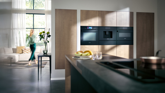 A Siemens kitchen with a women walking in the background