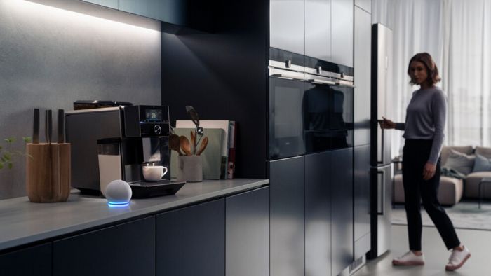 Amazon echo in the kitchen by Siemens coffee machine, with a woman opening a cupboard door