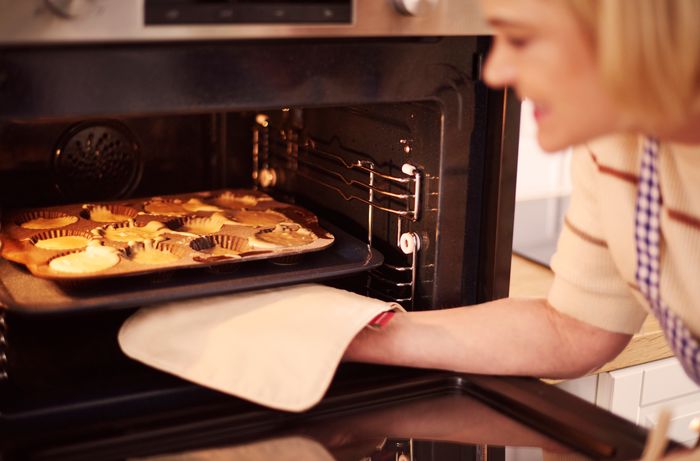 Donna che inforna una teglia di muffin nel forno di casa