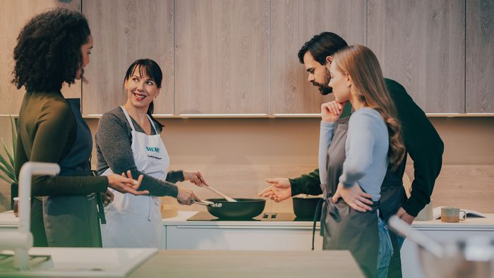 Personen stehen am Herd und kochen zusammen.